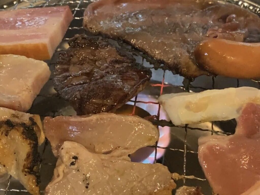 焼き台で肉やウインナーを焼いてる