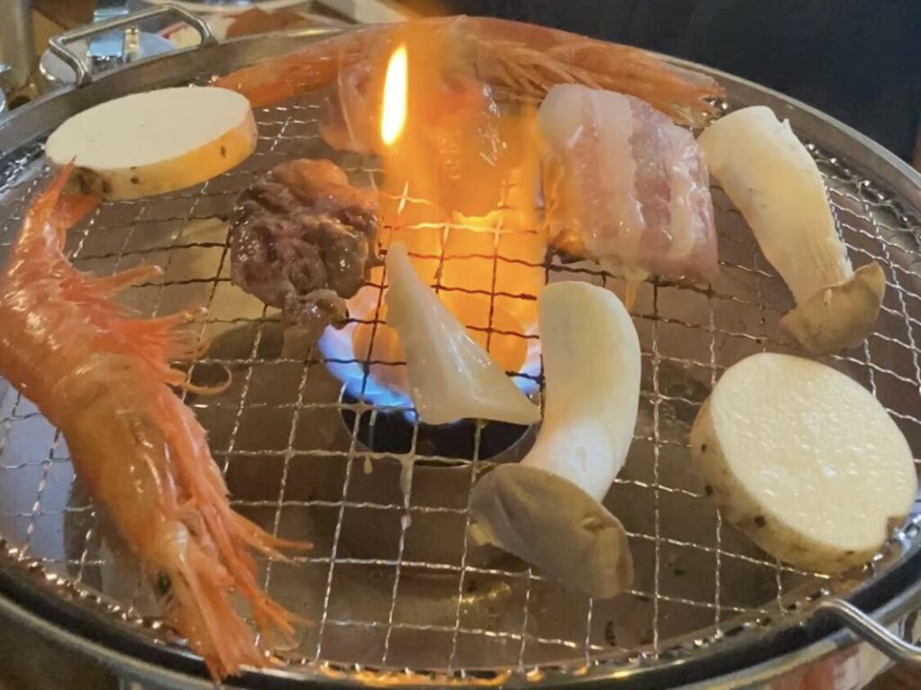 焼き台で海老や肉を焼いてる