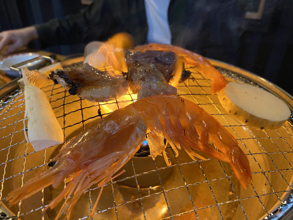 焼き台で海老や肉を焼いてる