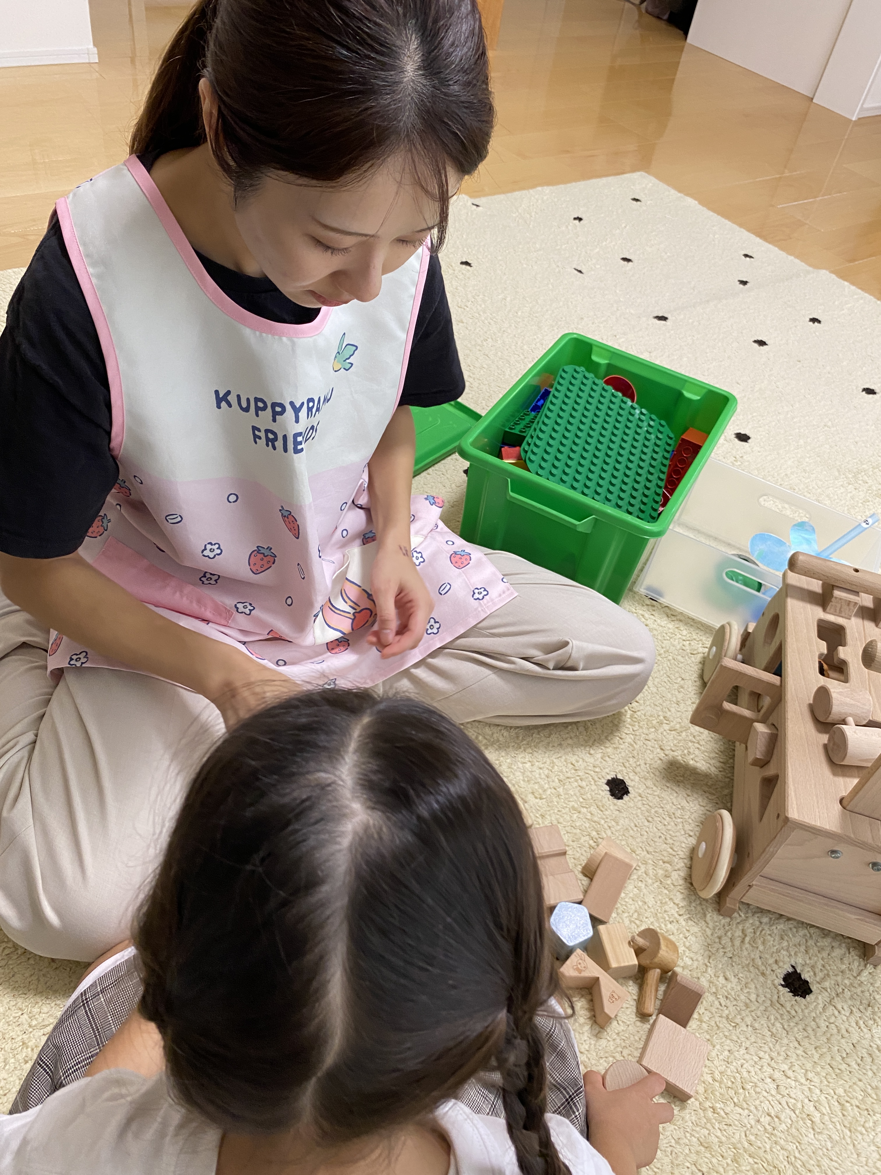 子どもの隣で木のおもちゃを使って遊ぶ引田さん